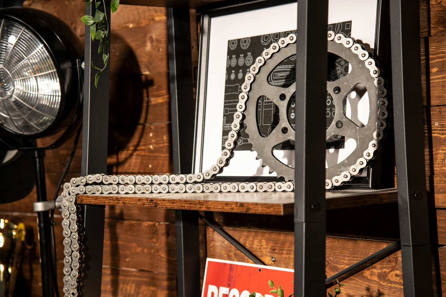 Metal chain and sprocket resting on a wooden shelf.
